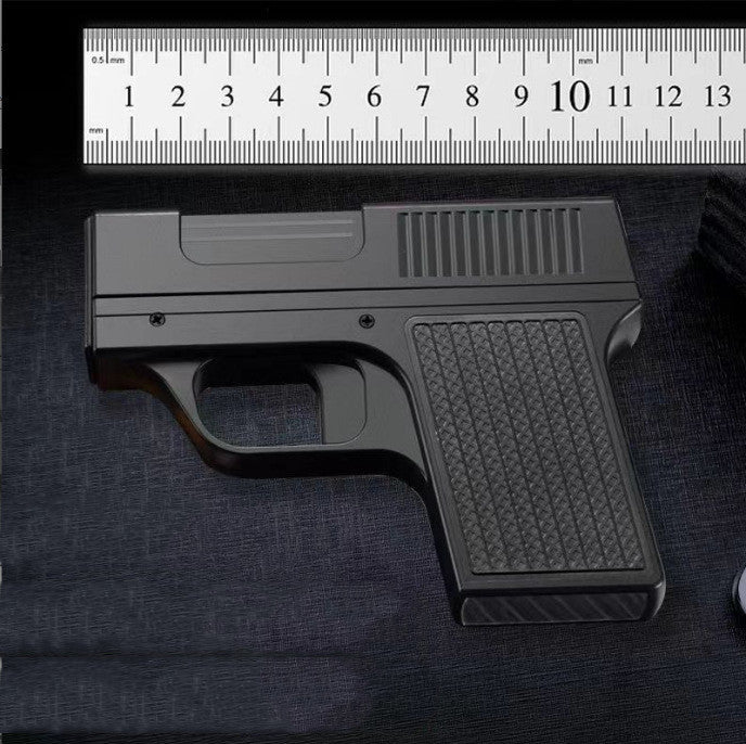 Black gun model on a dark surface with a ruler for scale.