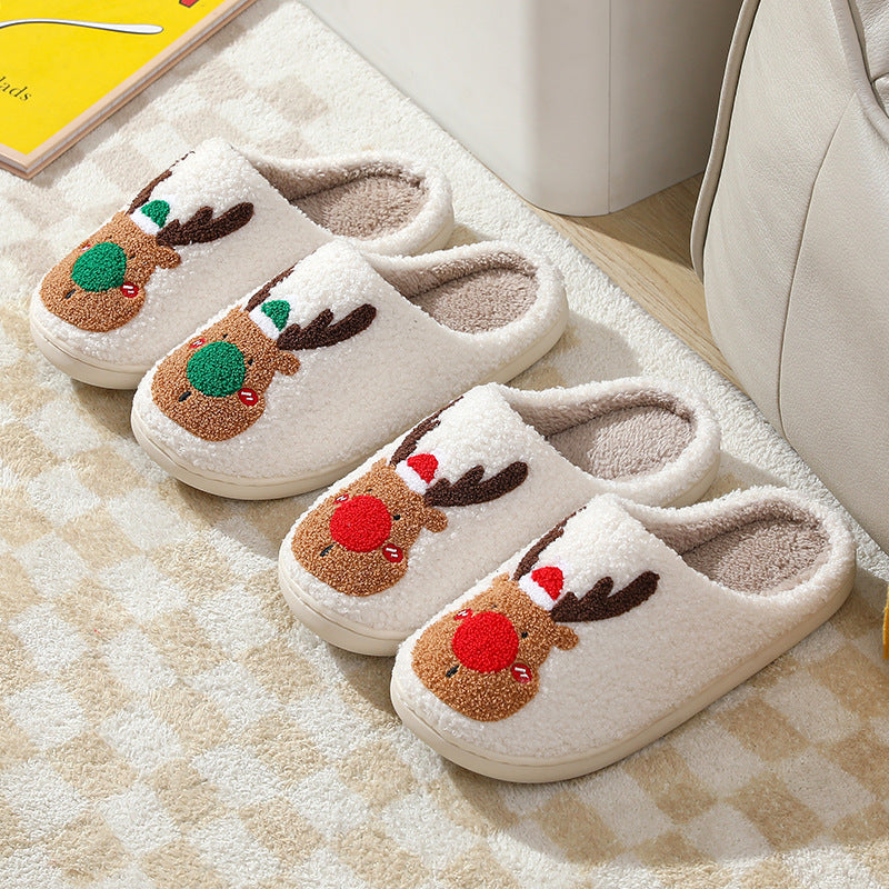 Pair of white slippers with reindeer design on a checkered floor.