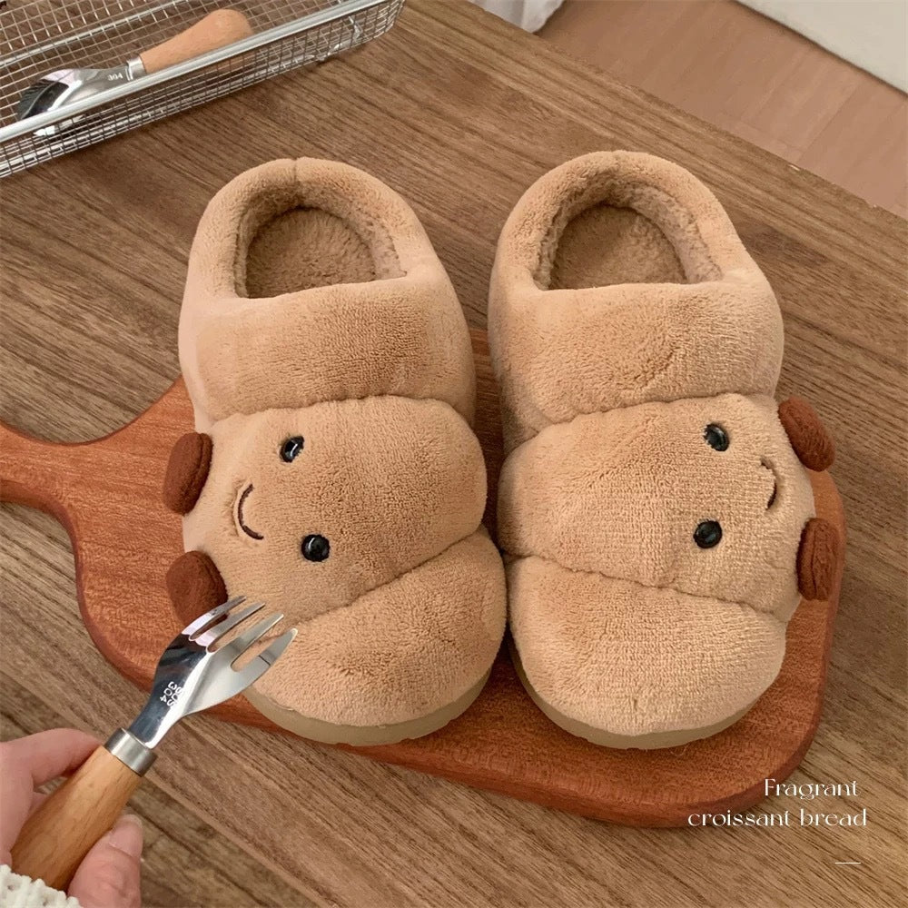 Pair of beige slippers with a smiley face design on a wooden board.