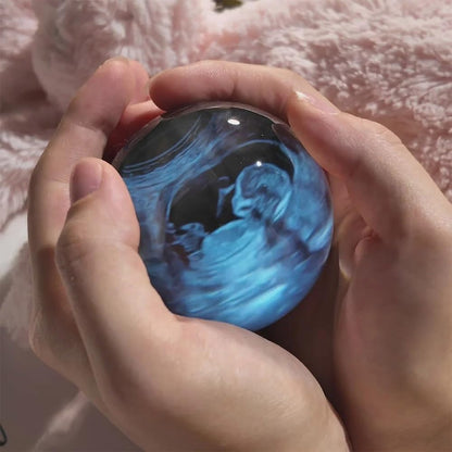 Hands holding a blue marble with a black and white design on a pink surface