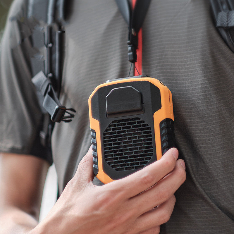 Person holding an orange and black portable speaker against a blurred background