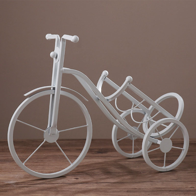 White decorative bicycle with a cart on a wooden surface and brown background