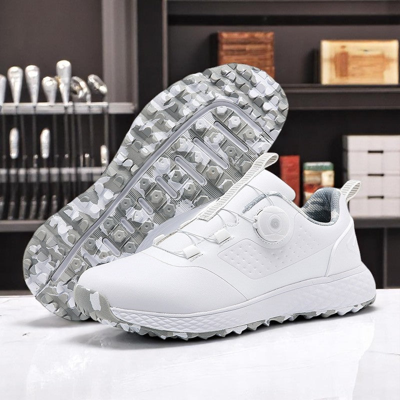 A pair of white golf shoes with a non-slip rubber sole, designed for all-terrain play on a green surface with golf balls and clubs in the background.