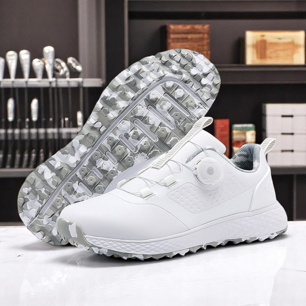A pair of white golf shoes with a non-slip rubber sole, designed for all-terrain play on a green surface with golf balls and clubs in the background.