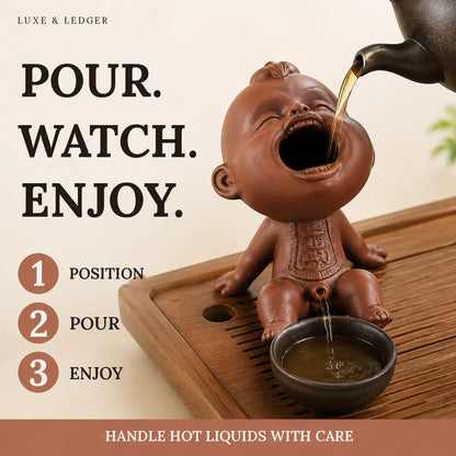 A terracotta-colored baby-shaped pouring tea accessory sits on a wooden tray, with tea being poured into a small cup. Large text reads 'POUR.