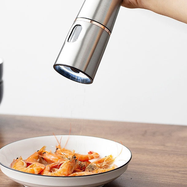 Metallic kitchen tool being used on a bowl of prawns on a wooden surface.