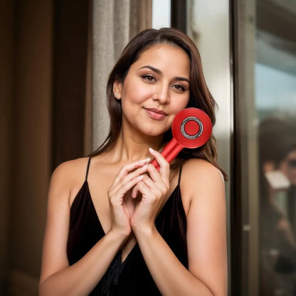 Woman holding a red hair dryer in a blurred indoor setting