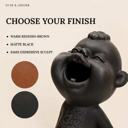A matte black sculptural figurine of a laughing baby or child, shown on a warm beige background with text reading 'CHOOSE YOUR FINISH' and two circular finish options: warm reddish-brown and matte black. 'LUXE & LEDGER' appears at the top.