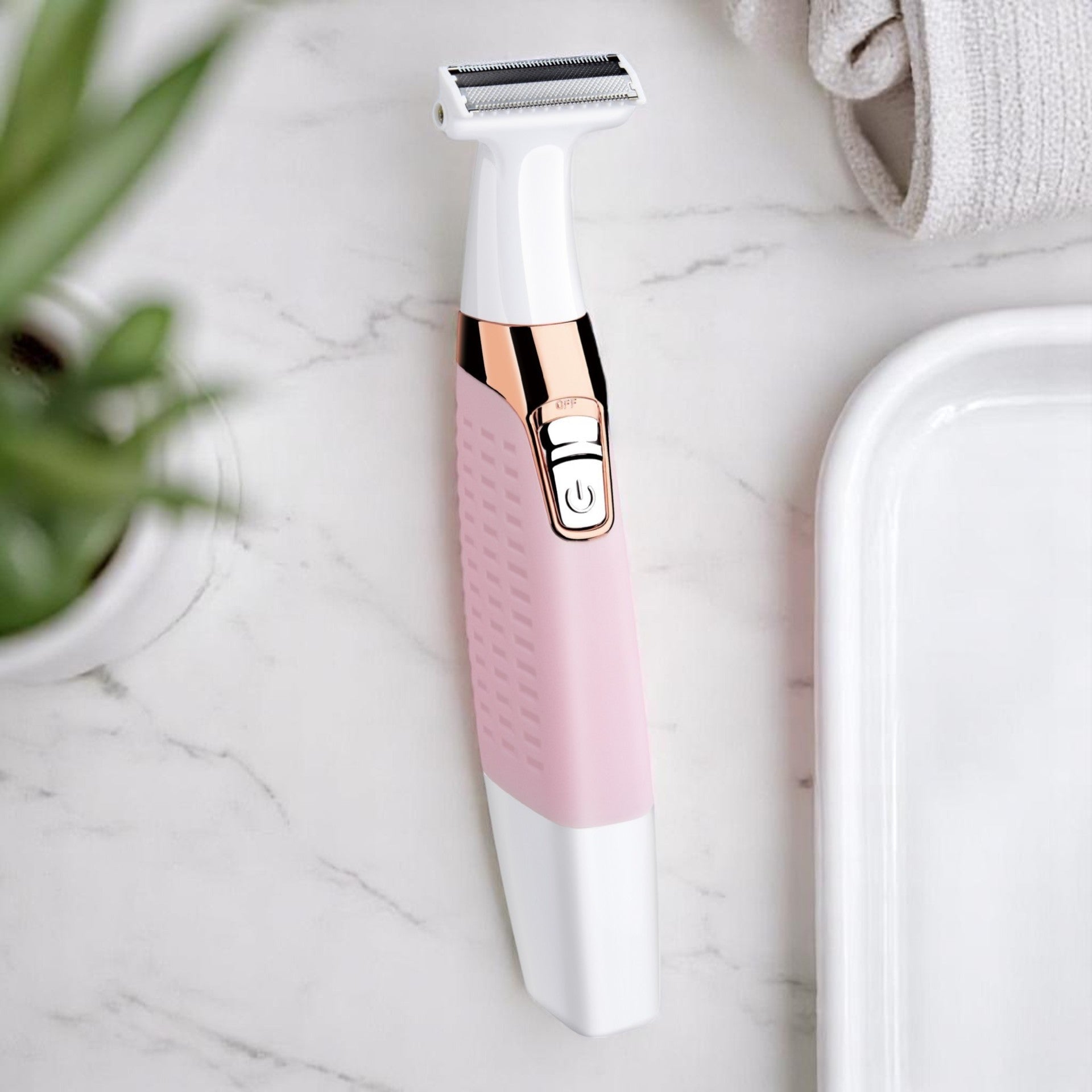 A blue and silver electric razor with a stainless steel blade, an ergonomic handle, and a USB recharge port, placed on a white surface next to a green plant and a white towel.
