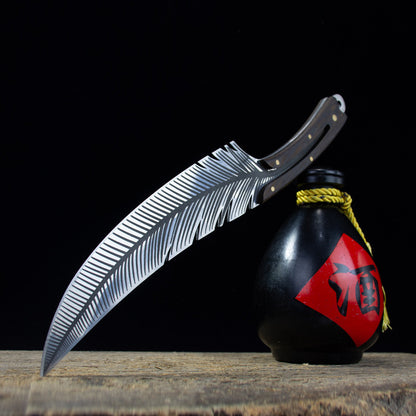 Forked blade knife leaning against a black container with red accents on a wooden surface.