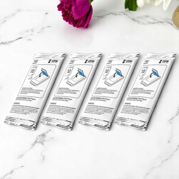 Four packages of Ztotop screen cleaning wipes on a marble surface with a pink flower in the background.