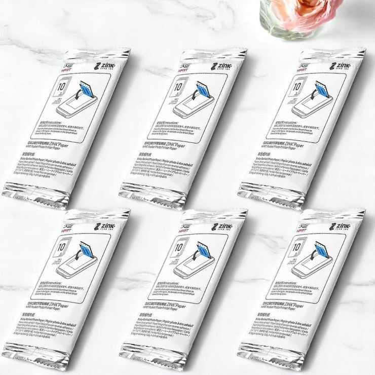 Multiple packages of ZTONE paper on a marble surface with a glass of water and flowers in the background.