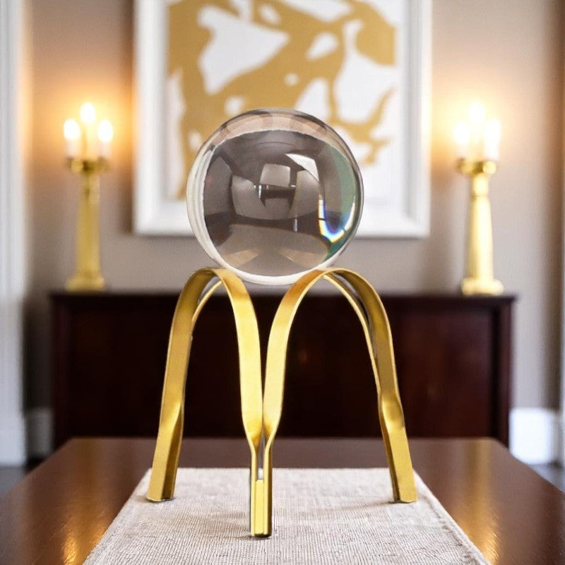 Decorative object with a gold base and clear sphere on a table