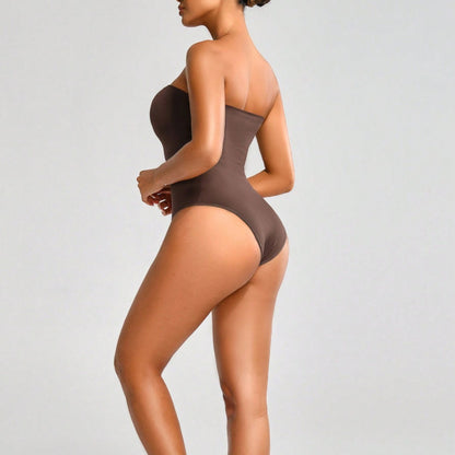 Woman wearing a brown bodysuit against a light gray background