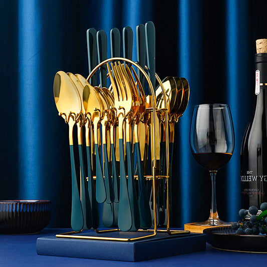 Set of gold and blue cutlery on a stand with a glass of red wine and a bottle in the background.