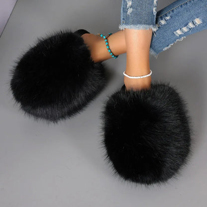 Black fluffy slippers worn with denim jeans on a gray background