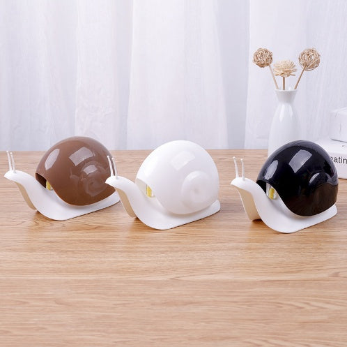 Three snail-shaped containers with different colored shells on a wooden surface.