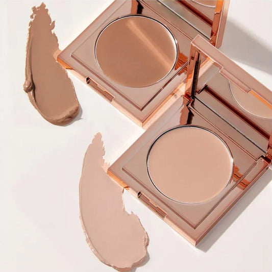 Makeup compact with open lid showing beige powder on a light background