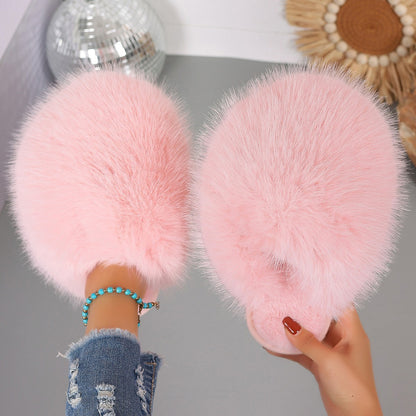 Pink fluffy slippers held by a person with a blurred background