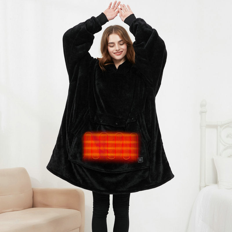 Person wearing a black heated poncho with visible heating element in a room.