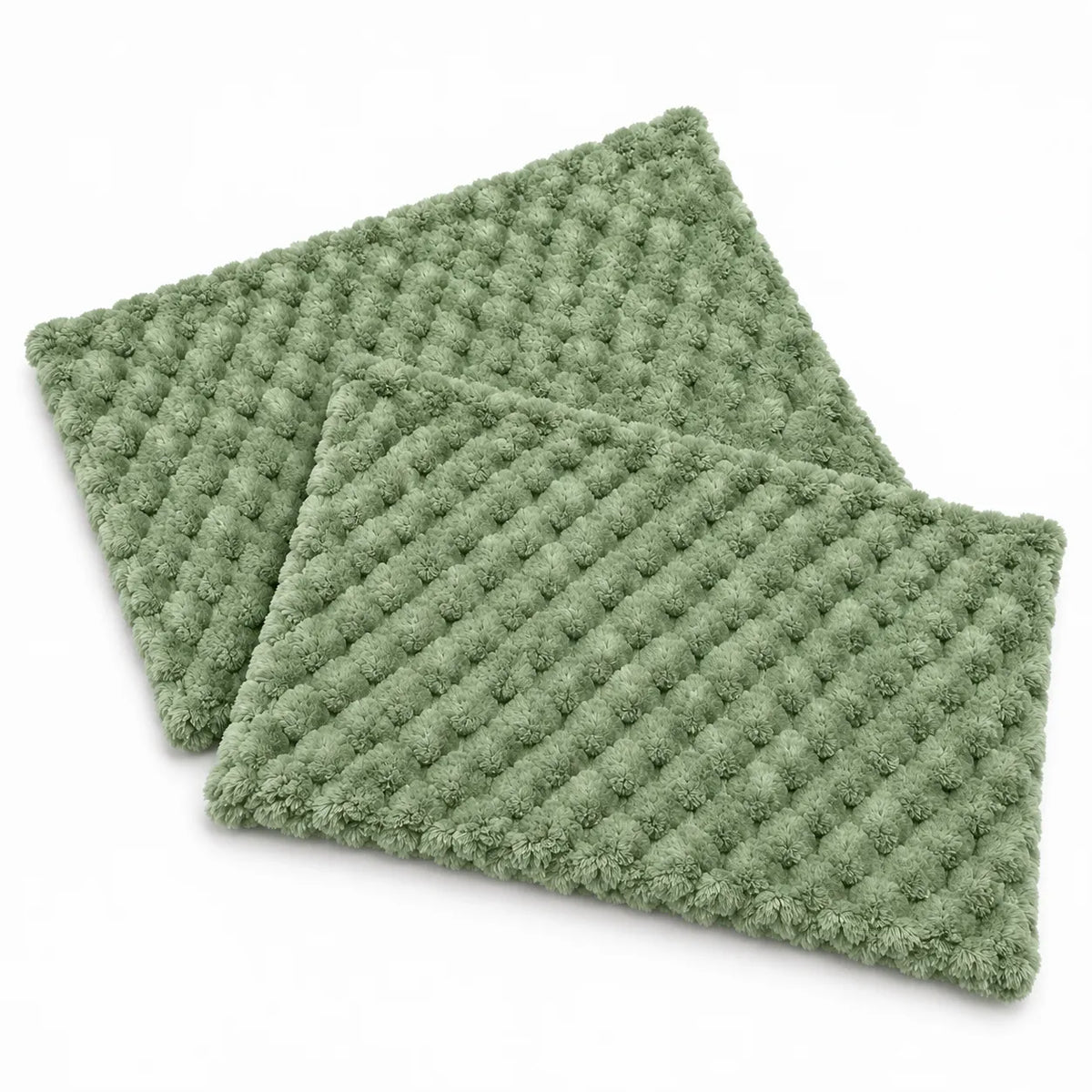 Two rectangular sage green textured bath mats with a raised tufted pattern, shown overlapping on a clean white background.
