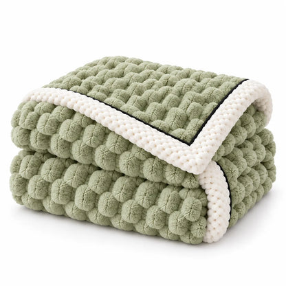 A folded textured blanket with a light sage green boucle-style surface and thick cream-colored trim, shown on a clean white background.