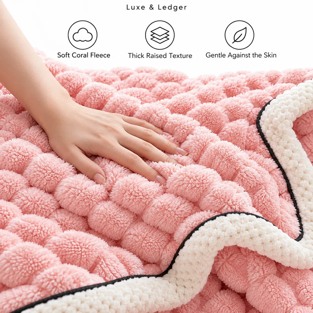 A close-up of a pink textured blanket with a raised bubble-like tufted pattern and a cream border with black trim. A hand is resting on the blanket, and text at the top reads 'Luxe & Ledger' with three feature callouts: 'Soft Coral Fleece,' 'Thick Raised Texture,' and 'Gentle Against the Skin.