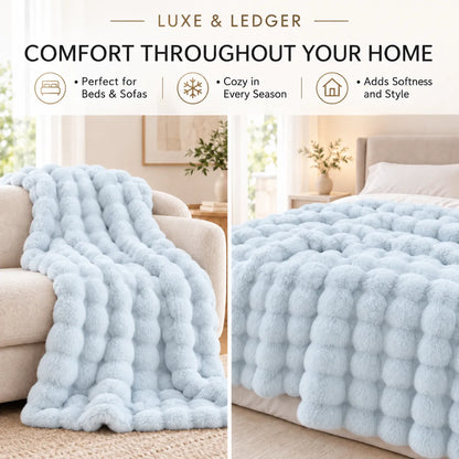 A light blue plush textured throw blanket shown draped over a beige sofa on the left and spread across a bed on the right, with marketing text at the top reading 'LUXE & LEDGER' and 'COMFORT THROUGHOUT YOUR HOME.'.