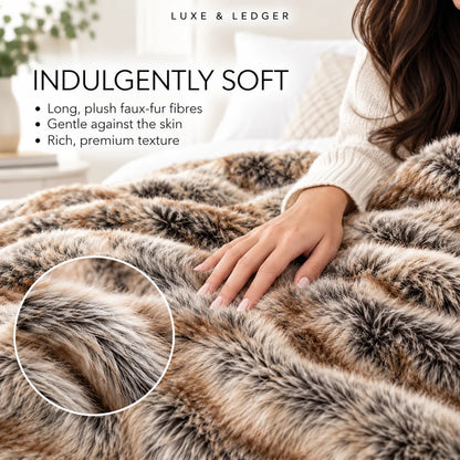 A person wearing a cream knit sweater rests under a plush faux-fur throw blanket with a brown and beige animal print. The image includes text reading 'INDULGENTLY SOFT' and bullet points about the long, plush fibres, plus a circular inset close-up of the fur texture.