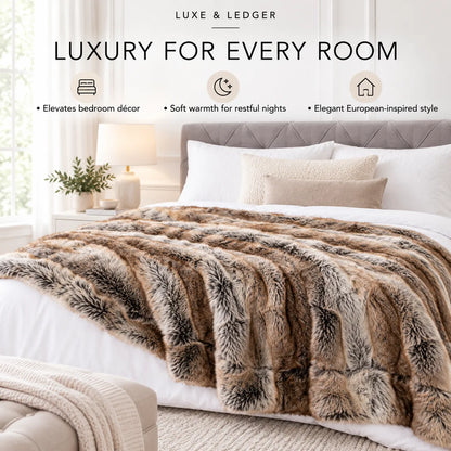 A plush faux-fur style throw blanket in mixed brown, beige, and gray tones draped over a bed in a softly styled bedroom. The scene includes pillows, a headboard, bedside lamp, plant, and text at the top reading 'LUXE & LEDGER' and 'LUXURY FOR EVERY ROOM'.