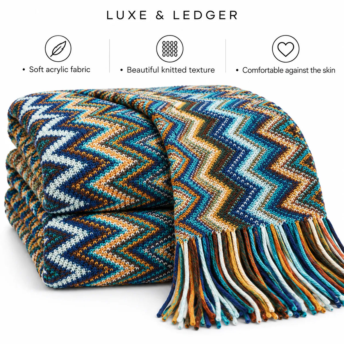 A folded multicolor knit throw blanket with fringe, shown on a white background with three feature icons and the text 'LUXE & LEDGER' above. The blanket has a zigzag chevron pattern in blue, teal, orange, brown, cream, and black.