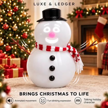 A white snowman Christmas ornament or toy with a black top hat, red-and-white striped scarf, and twig arms, centered in a cozy holiday living room scene with a lit fireplace, Christmas tree, stockings, and gift boxes. Text at the top reads 'LUXE & LEDGER' and text at the bottom says 'BRINGS CHRISTMAS TO LIFE' with feature icons.