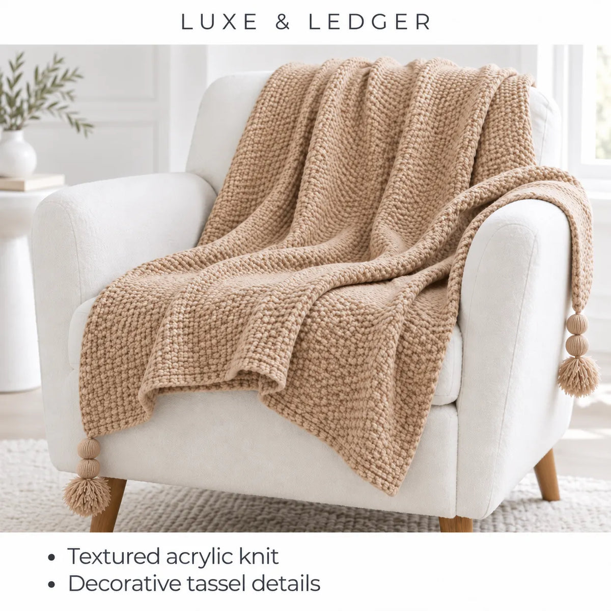 A chunky knit throw blanket in a warm beige/tan color draped over a white armchair in a bright, modern room. The text at the top reads 'LUXE & LEDGER', and the bottom text highlights 'Textured acrylic knit' and 'Decorative tassel details'.