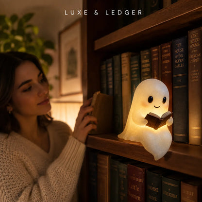 A cute ghost-shaped night light reading a book, placed on a wooden bookshelf next to a woman in a cozy room. The brand name 'LUXE & LEDGER' is visible at the top.