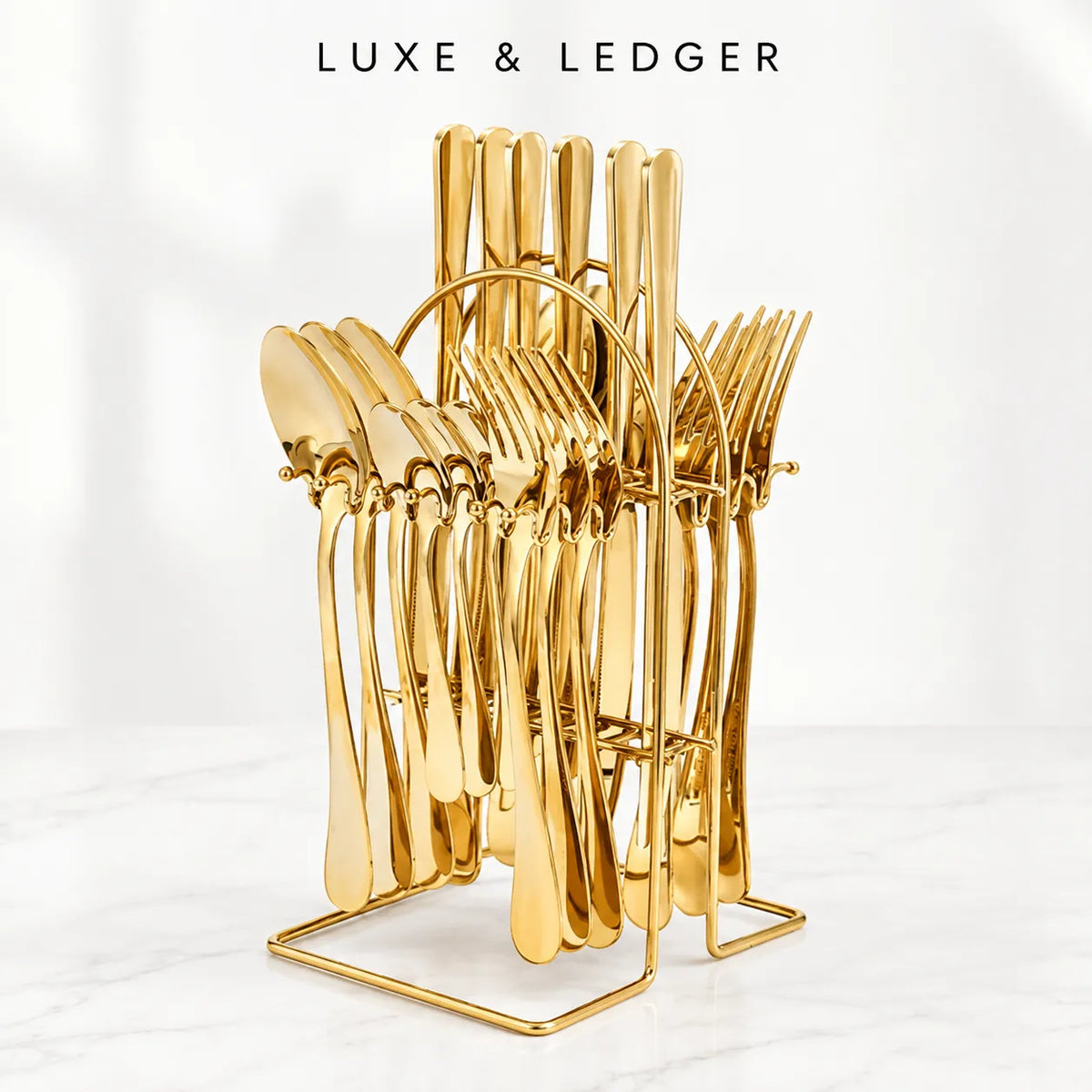 A gold-colored metal cutlery stand holding multiple polished utensils, photographed on a light marble surface against a soft white background. The text 'LUXE & LEDGER' appears at the top.