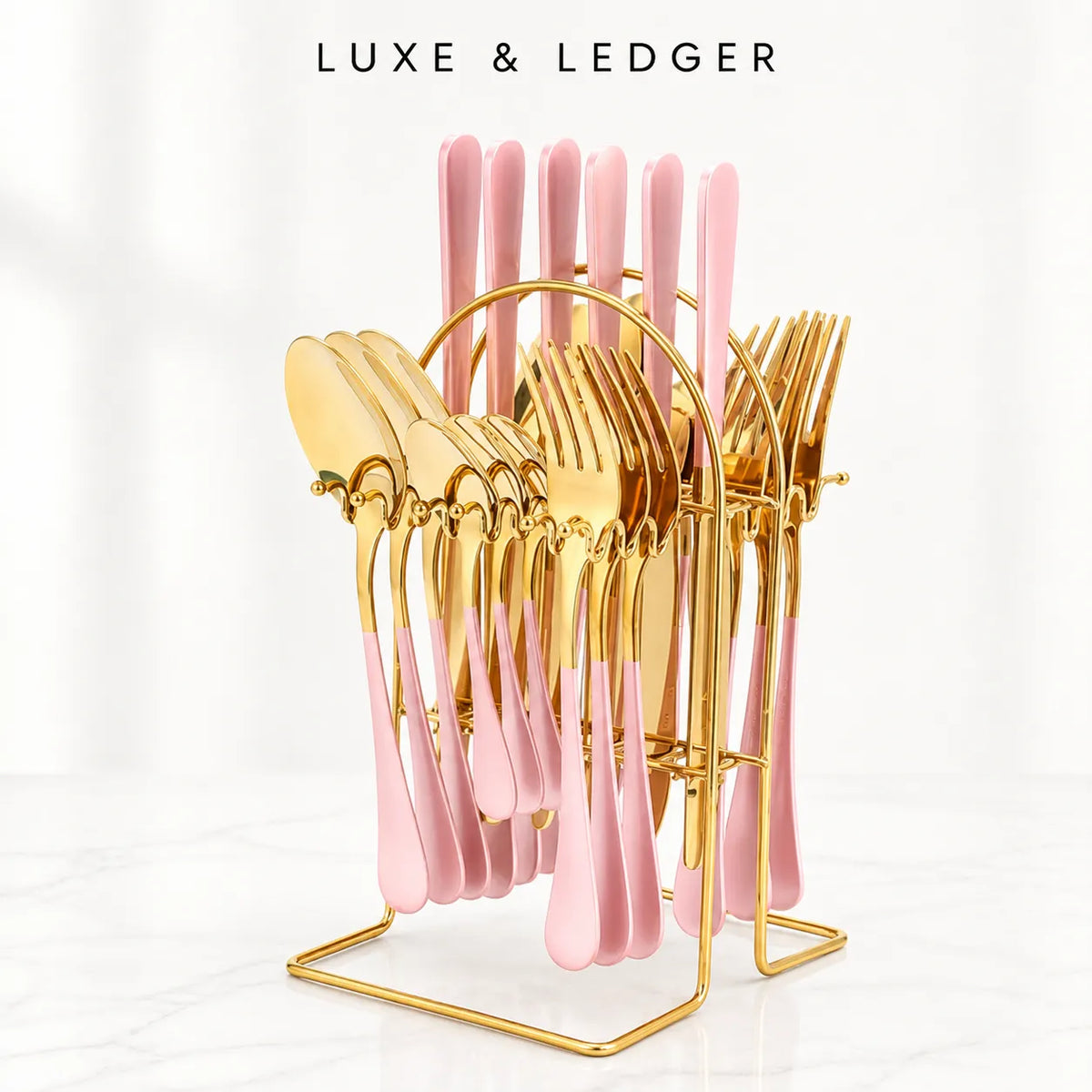 A luxury cutlery set with pink handles and gold metal heads, displayed on a gold wire stand. The set includes forks, spoons, and knives, with the brand name 'LUXE & LEDGER' printed at the top of the image.