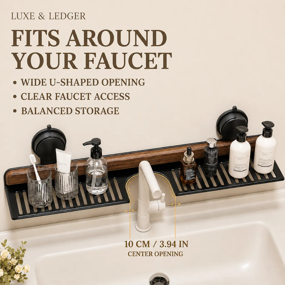 A bathroom sink faucet organizer mounted above a sink, shown with text callouts about fit around the faucet and 10 cm center opening. The organizer has two black suction-cup sections, a dark wood center panel, and a black slatted tray holding cups, soap dispenser, bottles, and a white faucet.