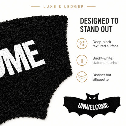 A promotional product graphic for a black textured rug or mat with bold white lettering. The left side shows a close-up of the black shaggy surface with part of a white word, while the right side contains marketing text reading 'DESIGNED TO STAND OUT' and feature callouts: 'Deep-black textured surface,' 'Bright-white statement print,' and 'Distinct bat silhouette.