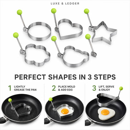 Six stainless steel breakfast mold shapes with green-handled clamps are shown on a white background, plus three instructional panels demonstrating how to use the molds in a frying pan to make eggs in heart, cloud, and star shapes.