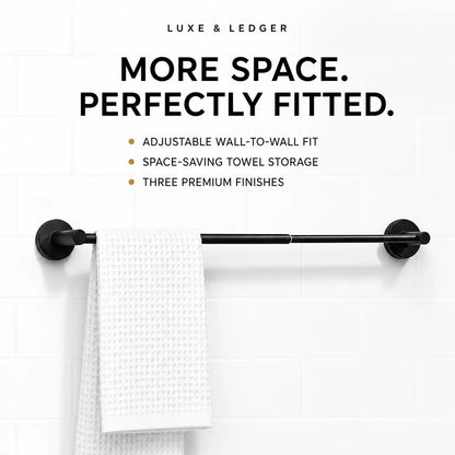 Black towel bar mounted on a white tiled wall, with a white textured towel hanging from the center. Text above reads 'LUXE & LEDGER' and 'MORE SPACE.