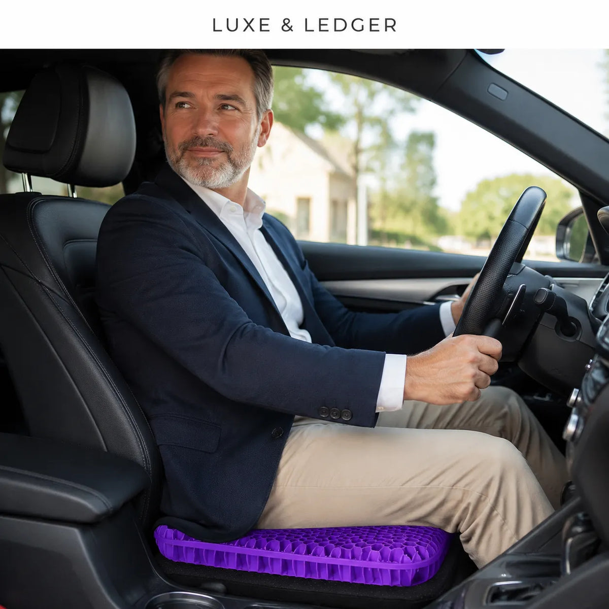A man in a navy blazer and beige pants sits in the driver's seat of a car, using a purple textured car footrest cushion. The brand name 'LUXE & LEDGER' is displayed at the top of the image.