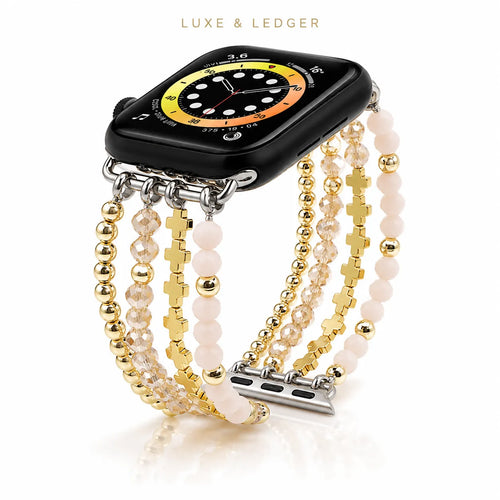A multi-strand watch band featuring gold-tone beads, pale pink beads, and gold-tone crosses, shown attached to a black smartwatch. The brand name 'LUXE & LEDGER' is printed at the top of the image.
