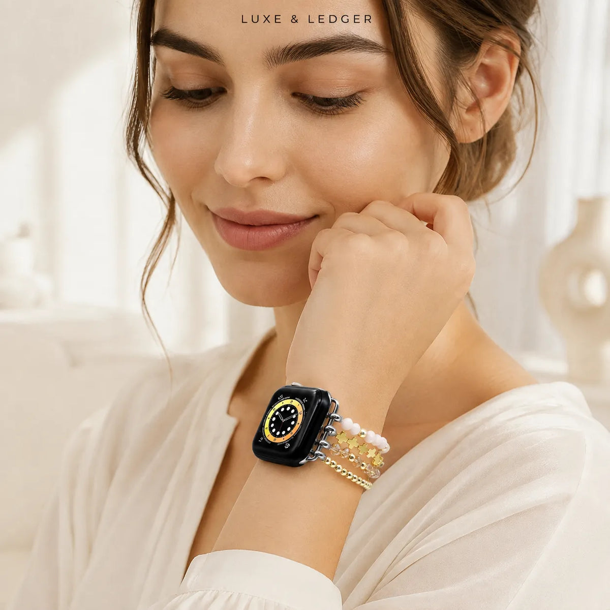 A woman wearing a black smartwatch with a gold-tone bezel and a multi-strand gold bracelet, in a bright, softly lit indoor setting. The brand name 'LUXE & LEDGER' is printed at the top of the image.