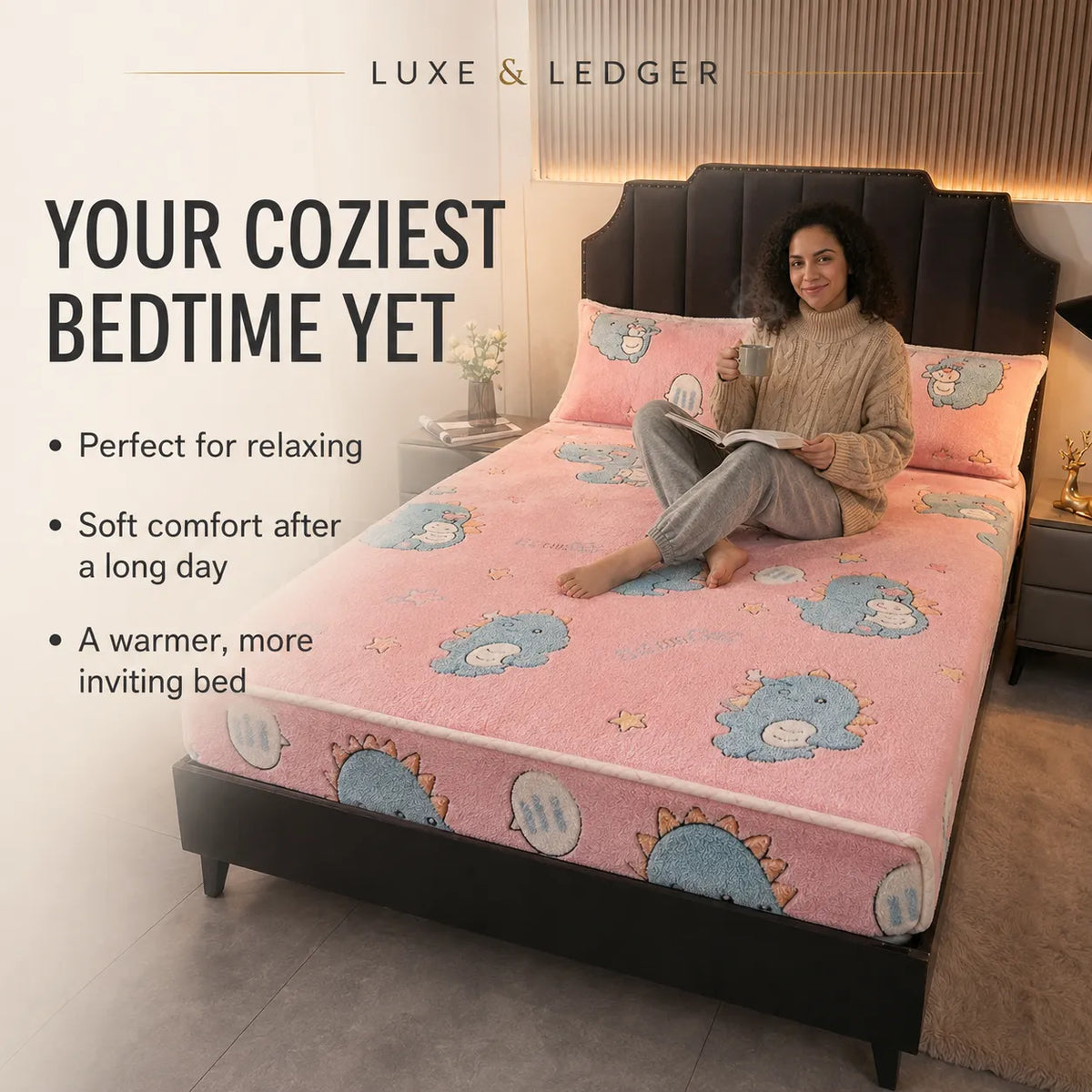 A woman sits on a bed wearing a cozy knit sweater and pajama pants while reading a book. The bed is made with a pink plush bedding set featuring a cartoon dinosaur pattern.