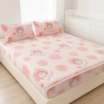 A pink bed sheet set with two matching pillowcases on a bed. The sheet and pillows feature a cute cartoon cat character inside a pink heart, surrounded by pink peach-like circles and small flowers, with the word 'Lovely' printed in blue.