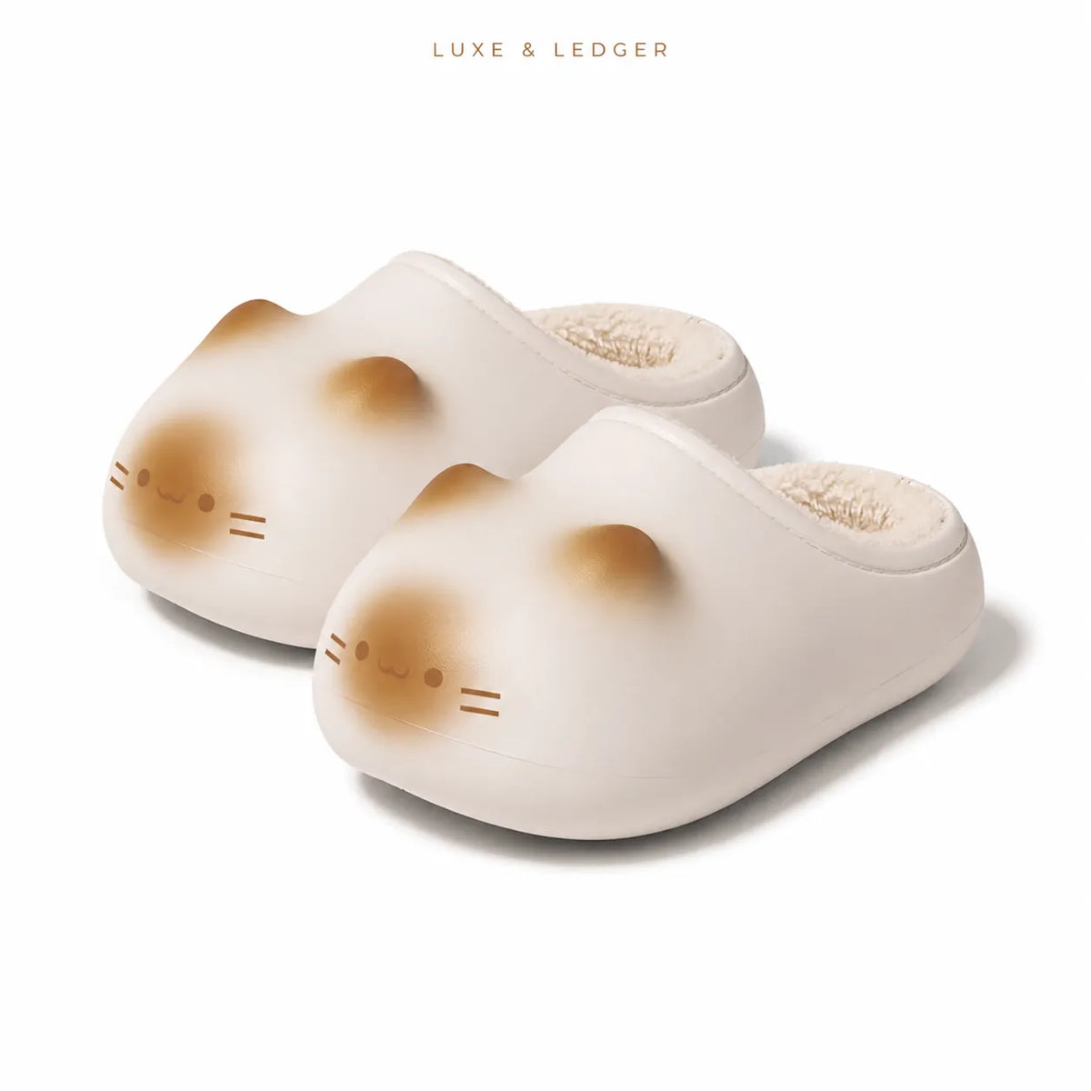 A pair of cute cat-shaped slip-on slippers in a warm cream color with brown accents for the cat's face and ears, featuring a soft fleece lining. The brand name 'LUXE & LEDGER' is printed at the top of the image.