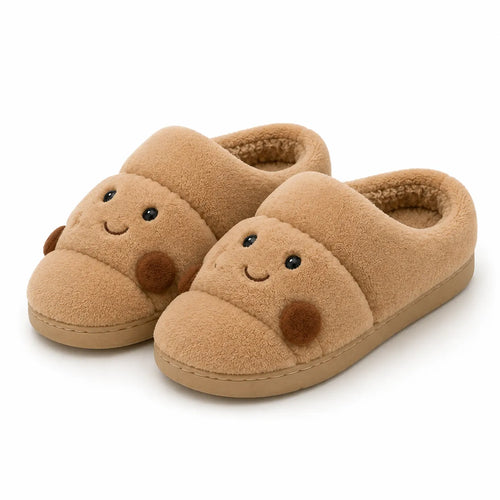 A pair of plush tan slipper shoes with a cute cartoon face on the toe, featuring embroidered eyes and a stitched smile, set against a plain white background.