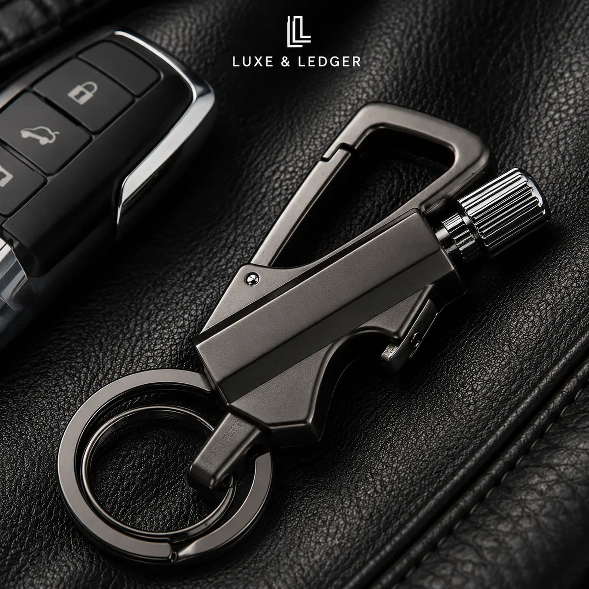 A dark metallic car keychain tool with a carabiner clip, ring, and textured knob, displayed on black leather next to a car key fob. The brand name 'LUXE & LEDGER' is visible at the top.