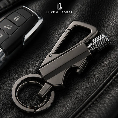 A dark metallic car keychain tool with a carabiner clip, ring, and textured knob, displayed on black leather next to a car key fob. The brand name 'LUXE & LEDGER' is visible at the top.