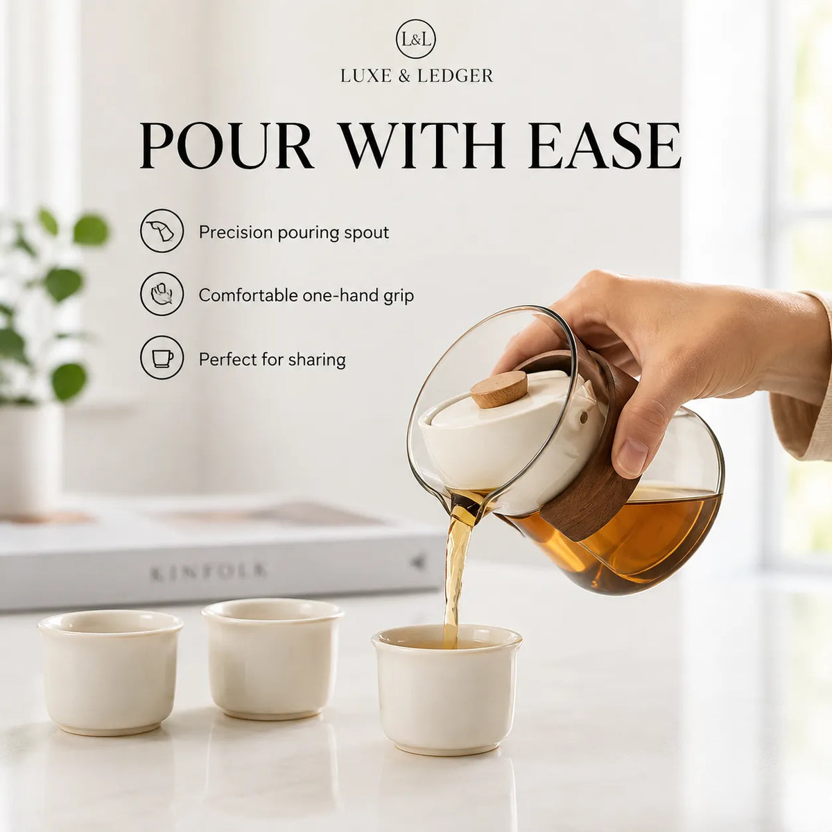 A hand pours amber tea from a glass teapot with a white lid and wooden handle into three small cream-colored cups on a bright white table. Text on the image reads 'POUR WITH EASE' and lists features including precision pouring spout, comfortable one-hand grip, and perfect for sharing.